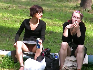 Hot babes with spread legs are drinking some coke outside right on the grass